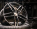 new expensive cast aluminum disc wheel black color, photographed on the tire. dark background, close-up